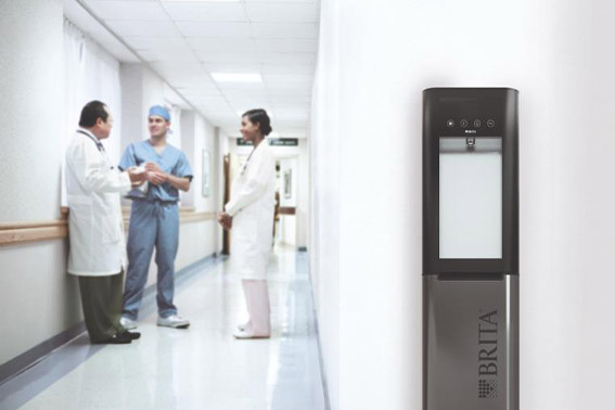 Flur in einem Krankenhaus, an einer Wand steht ein BRITA VIVREAU Sodamaster 200 – Standgerät