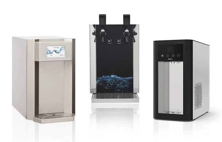 Drei Auftisch-Wasserspender nebeneinander. Links ein kompaktes Modell mit einem Bildschirm zur Steuerung, in der Mitte ein Wasserspender mit zwei Zapfhähnen für verschiedene Wassertemperaturen und rechts ein modernes, elegantes Gerät mit einfacher Bedienung für frisches Wasser. Jakob Wassertechnik bietet Wasserspender für Ihre Firma.