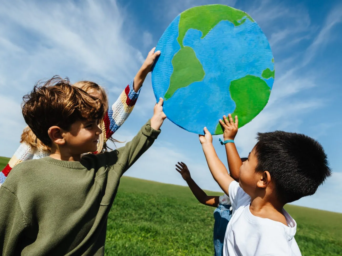Children learning about the world with globe outdoors